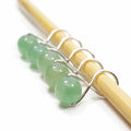 Five green aventurine bead infinity ring stitch markers on bamboo knitting needle