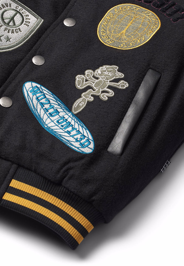Black jacket with various embroidered patches on a white background