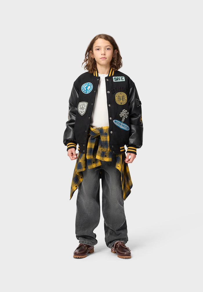 Person wearing a varsity jacket with patches on a white background