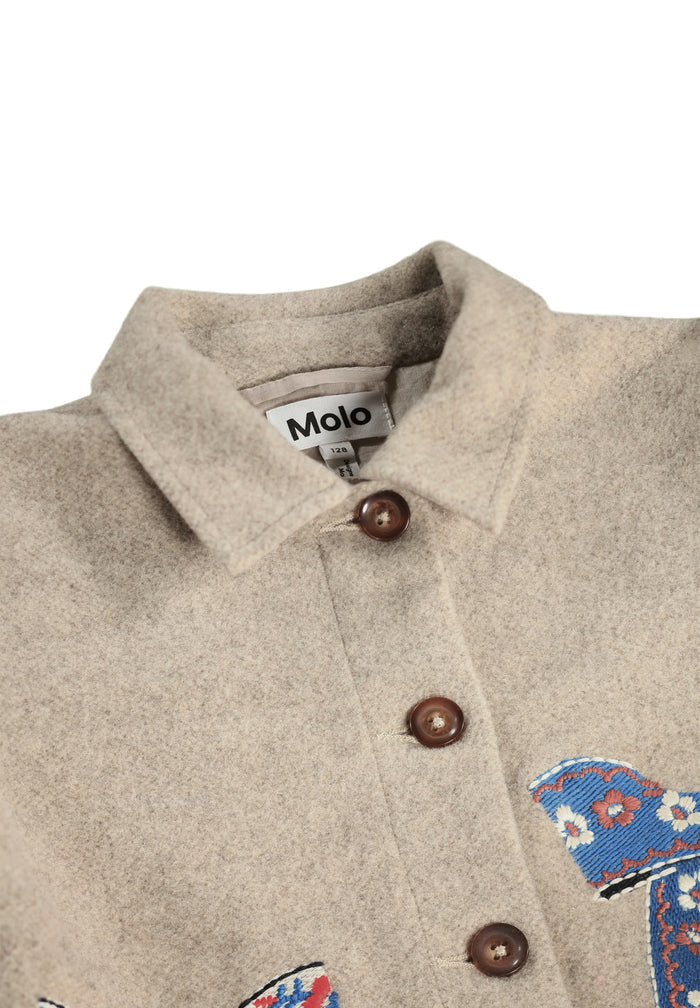 Close-up of a beige jacket with brown buttons and embroidered designs on a white background, featuring the Molo brand.
