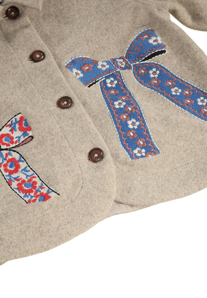 Close-up of a beige fabric with embroidered blue and red floral ribbons.