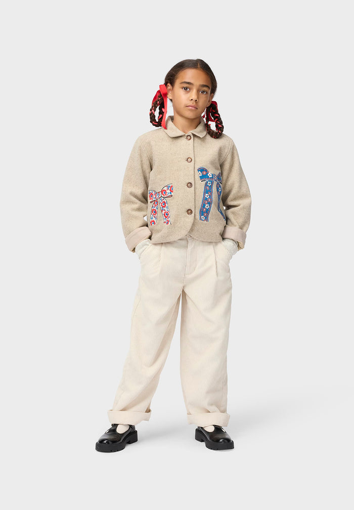 Child wearing a beige jacket with colorful patterns on a white background
