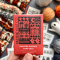 Hand holding the red Haunted Doodle Card Deck by Pacific Knit Co tuckbox
