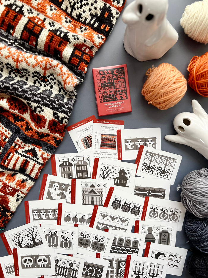 Haunted Doodle deck and chart cards scattered with ghost figurines and grey yarn