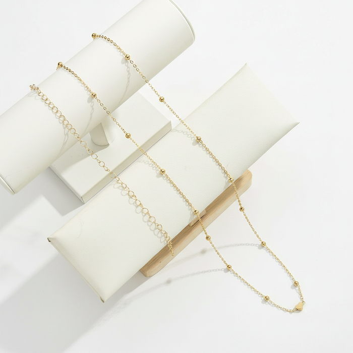 A shimmering silver-toned jewelry set featuring a tapered V-shaped mesh necklace and matching linear drop earrings on a white minimalist mannequin bust.