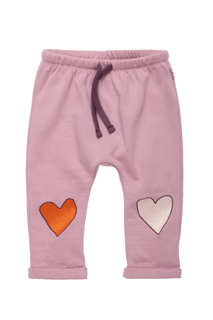 Pink knit pants for toddlers featuring an orange embroidered heart on the left leg and a white embroidered heart on the right leg, with a dark purple drawstring waistband.