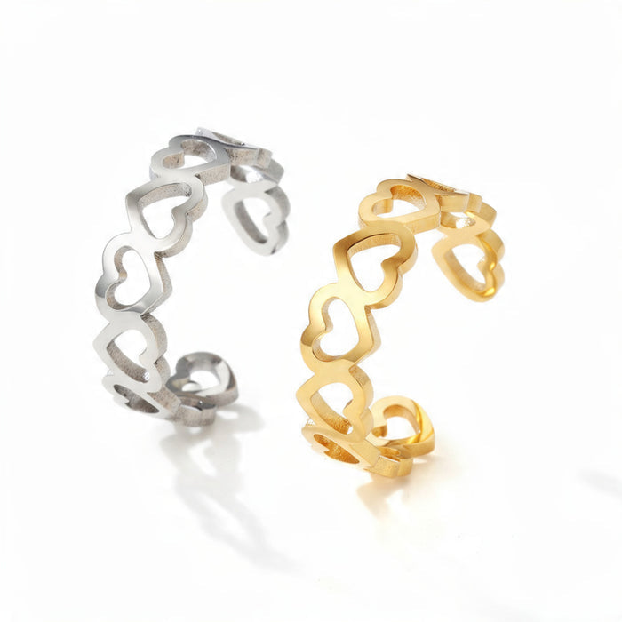 Two adjustable open rings with heart-shaped cutouts, one in polished silver and one in polished gold, displayed side by side on a pure white background.