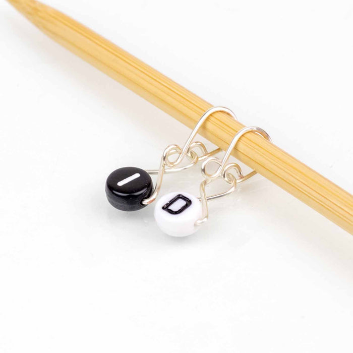 I and D letter bead stitch markers on silver wire hooks hanging from bamboo knitting needle