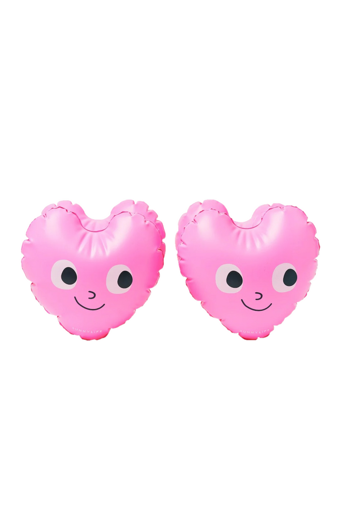 Two pink peach-shaped arm bands with faces on a white background