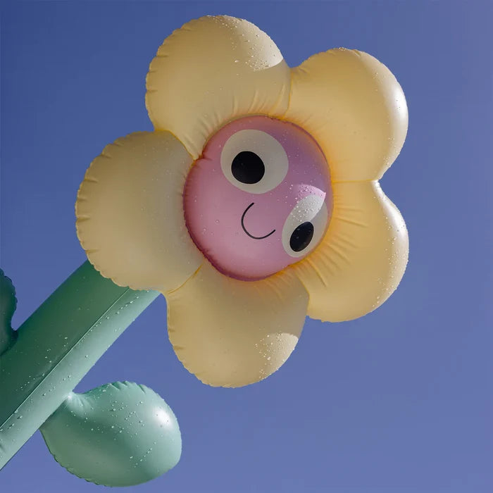 Toy figure of a flower with a smiling face against a blue background