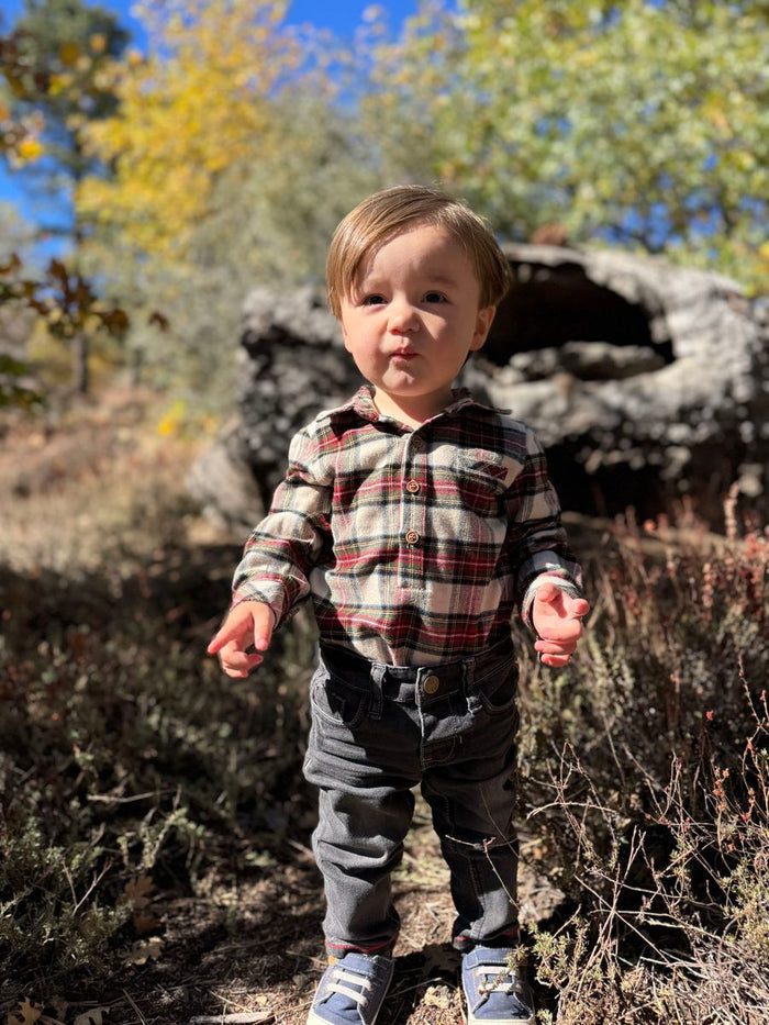 Child wearing plaid onesie.