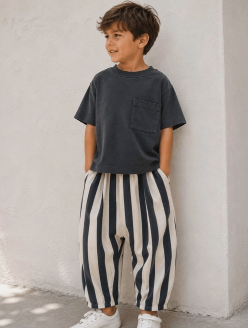 child posing in charcoal grey tee and charcoal and cream colored slouchy pants