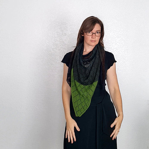 Front view of model wearing the Kellerwald shawl in green and black, with the black lace section draped at the neck and green triangle hanging down over a black dress