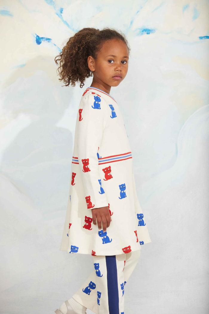 Child wearing a white outfit with blue and red patterns against a light background