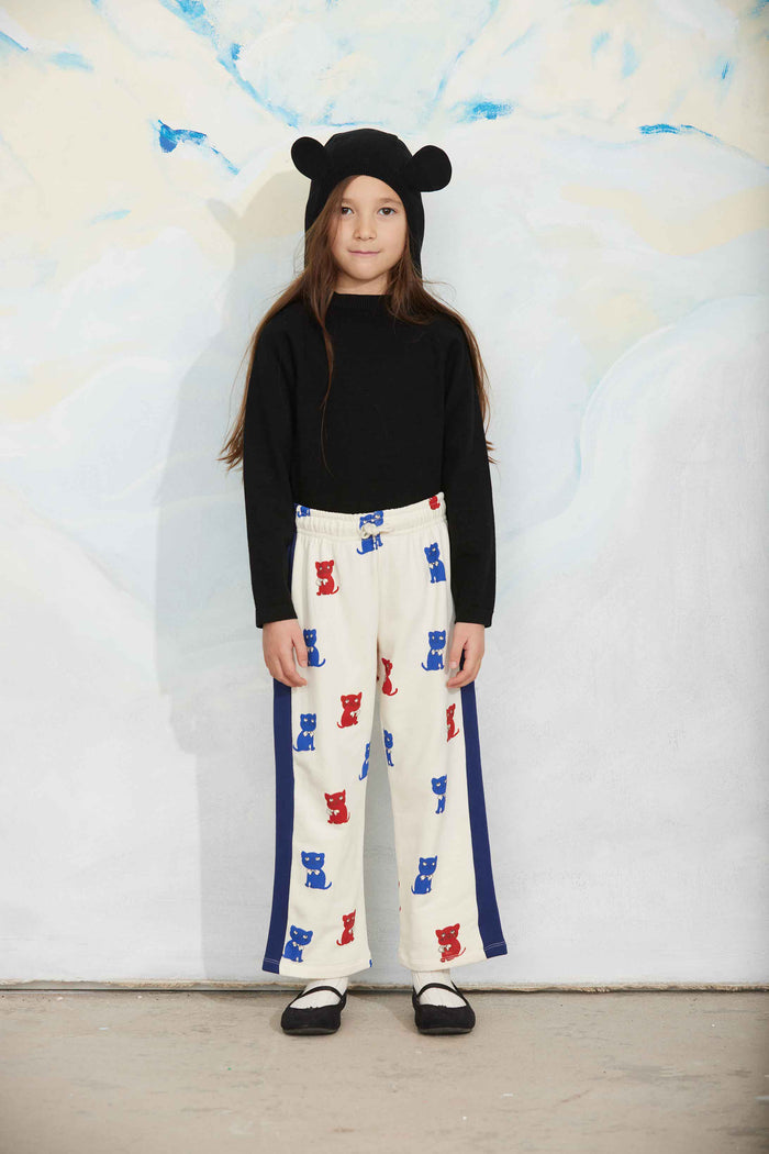 Child wearing a black sweater and colorful pants with a bear hat against a white background