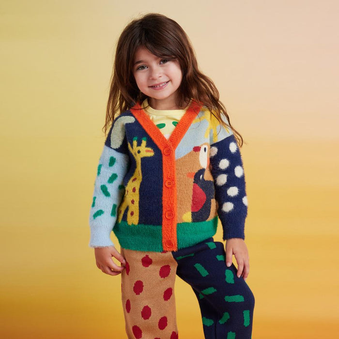 Child wearing a colorful sweater and pants with abstract patterns on a yellow background