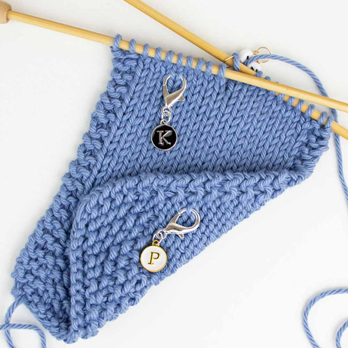 K and P reminder clip markers attached to blue knitting swatch showing knit side with K marker and purl side with P marker