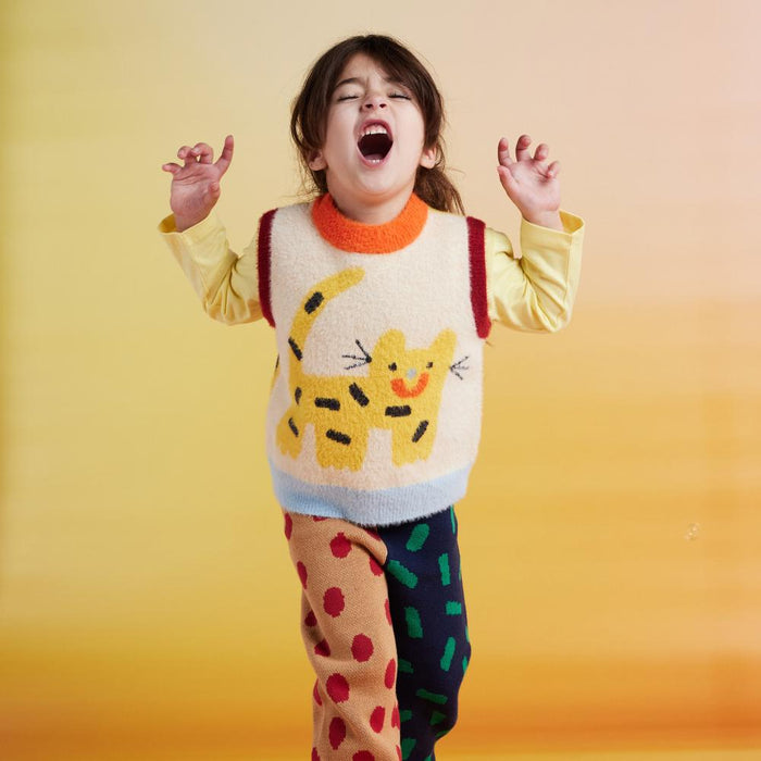Child wearing a colorful sweater with a cat design against a yellow background