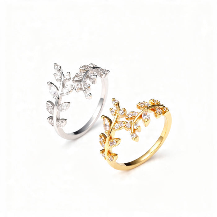 Two adjustable open rings designed as delicate branches with marquise and round crystals, shown in polished gold and silver finishes, centered on a pure white background.