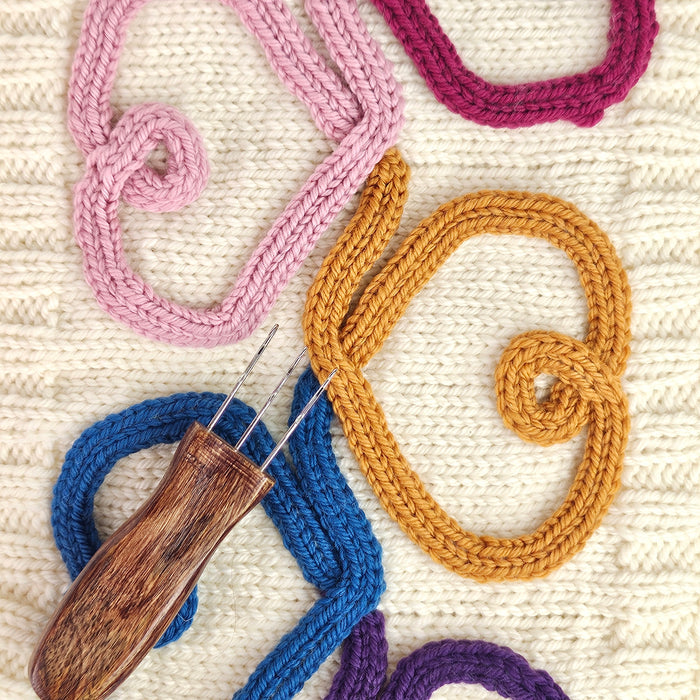 Finished freeform i-cord cable designs in cream and tan yarn showing decorative swirl and loop shapes created with the Cord Quill technique