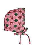 A pink bonnet in corduroy, decorated with a pattern of red flowers and green leaves, featuring tie straps at the bottom.