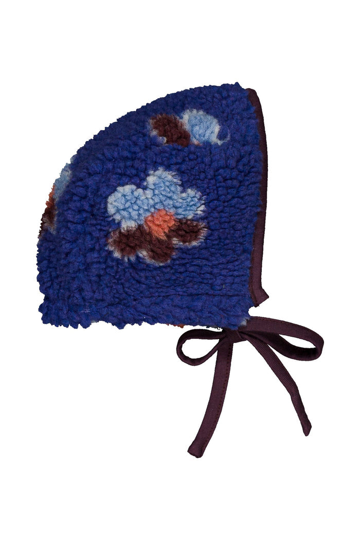 A royal blue fleece bonnet with embroidered floral motifs in light blue, brown, and orange, finished with dark plum ribbon ties, shown on a plain white background.