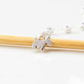 Close-up of silver scottie dog charm on numbered bead chain row counter resting on bamboo knitting needle