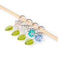 Little Flowers melody clip stitch markers with glass flower beads in pink, clear, teal, and blue with green leaf charms on bamboo needle