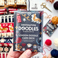 Hand holding the London Destination Doodle Card Deck foil pack by Pacific Knit Co