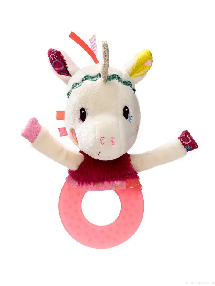 A plush unicorn baby teether toy with a pink ring handle, featuring a cream-colored face, patterned ears, a green headband, a magenta dress, and a textured pink ring.