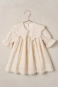 baby dress on a hanger against a beige background
