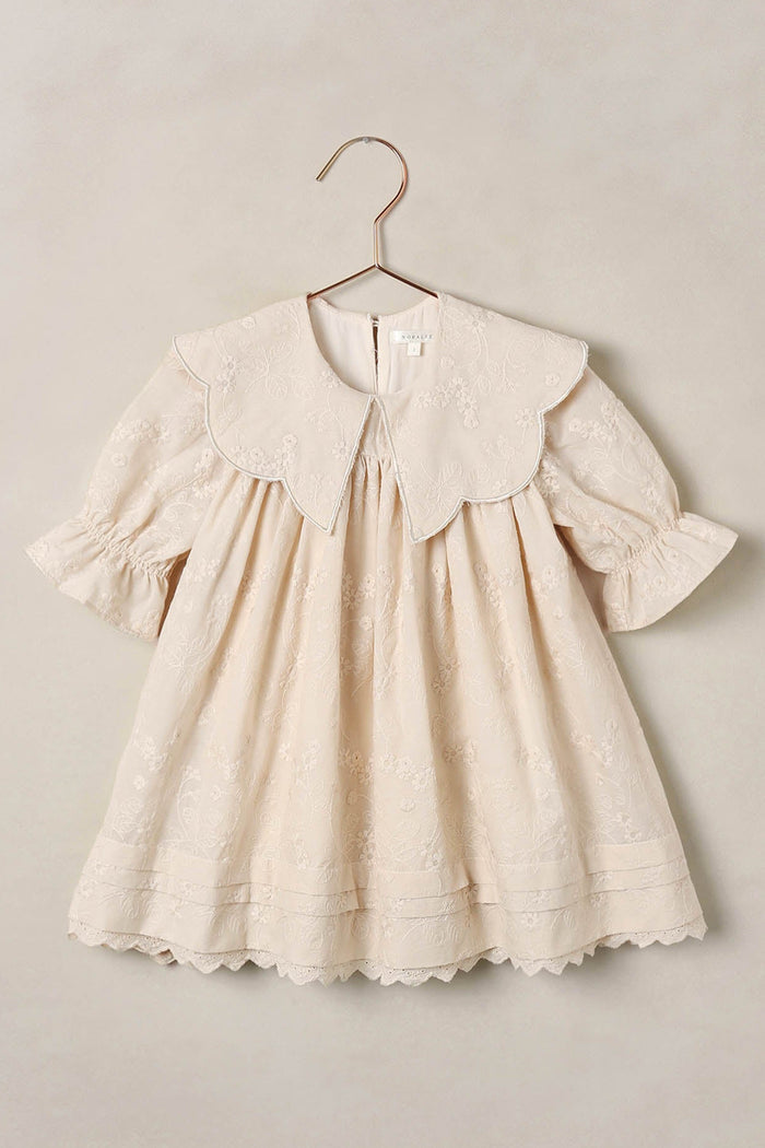 baby dress on a hanger against a beige background