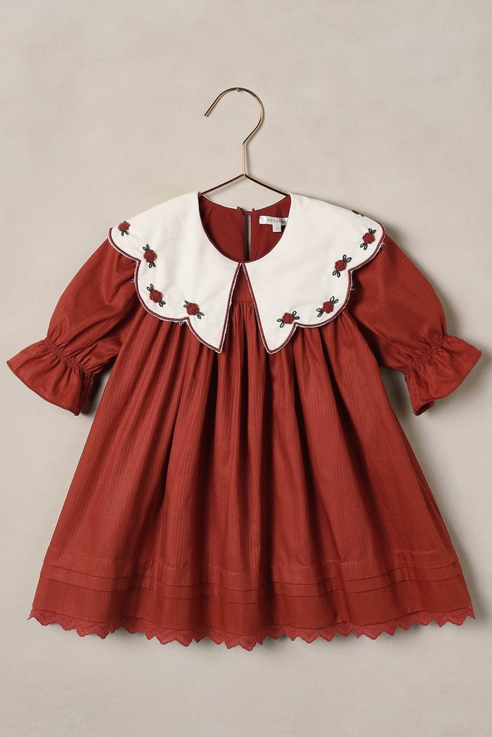 Red dress with white collar on a beige background