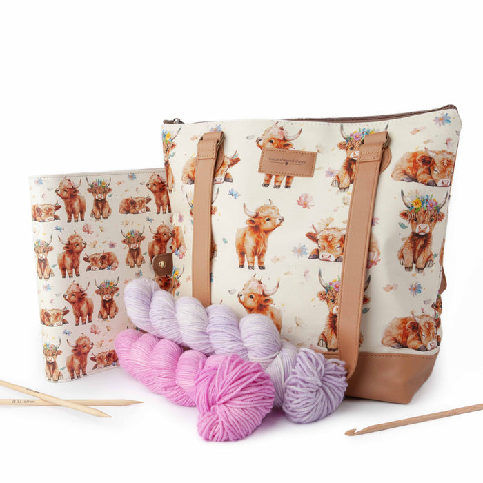 Maisy Highland Cow Mega Trinity Bag shown with knitting project contents — yarn balls in pastel colors, wooden needles, and a work in progress — demonstrating its capacity