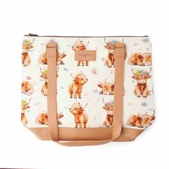 Maisy Highland Cow Mega Trinity Bag back view showing the highland cow print fabric, tan leather handles, and zippered top closure