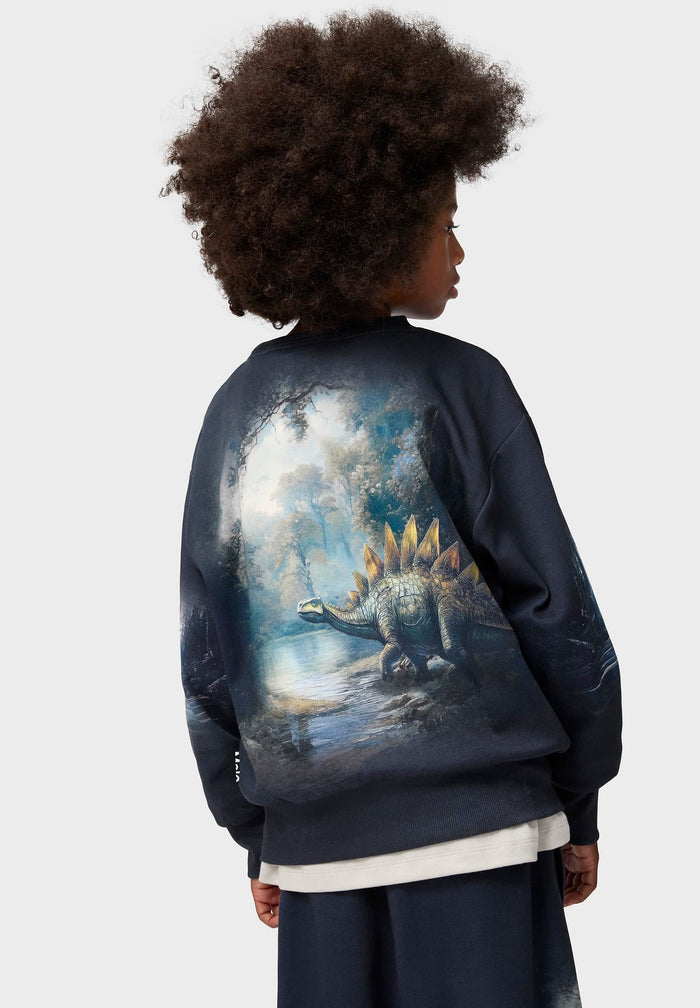 Person wearing a dark blue sweatshirt with a dinosaur graphic on the back against a white background