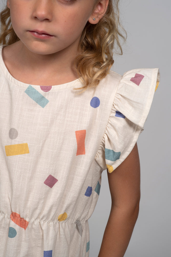 Child wearing a dress with colorful geometric patterns on a plain background