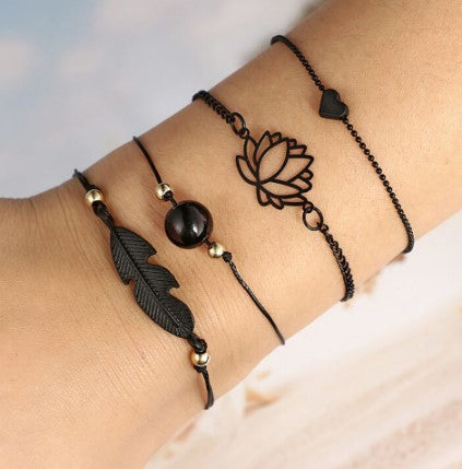 Bohemian style jewelry set featuring matte black metal bracelets with lotus and feather motifs worn on a wrist.