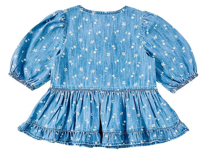 A blue denim-like baby dress with a white floral pattern, featuring short puff sleeves, a ruffled waist, and a tiered ruffle hem, shown against a plain white background.