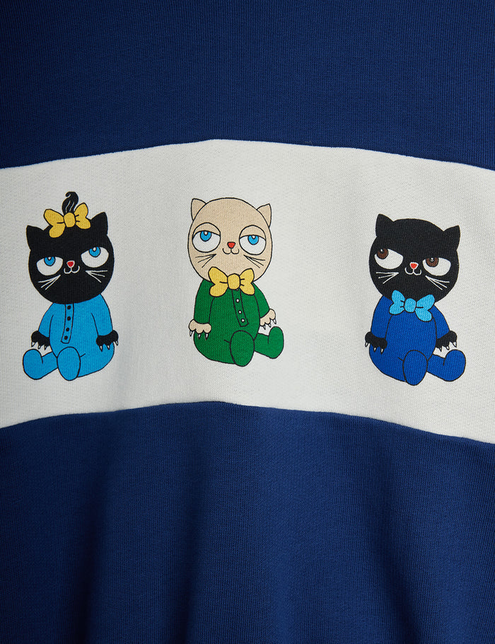 Three cartoon cats in blue, green, and black outfits with bow ties on a blue and white background.