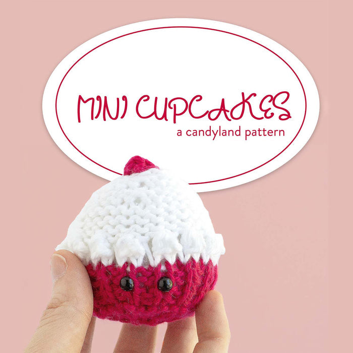 Mini Cupcakes candyland knitting pattern cover showing hand holding pink and white knitted cupcake with safety eyes