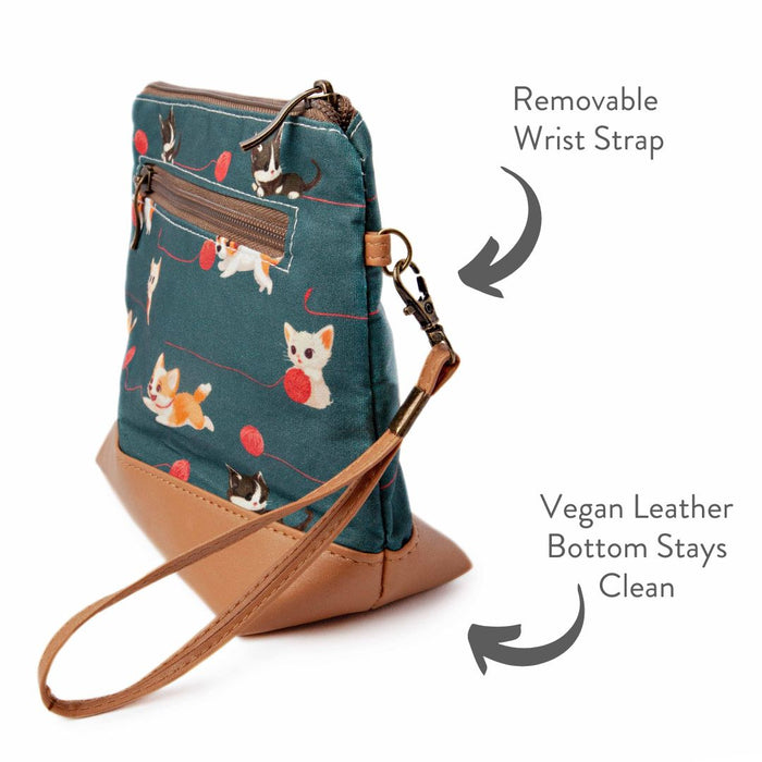 Cats and Dogs Mini Trini Bag side view showing the removable wrist strap, zippered exterior back pocket, and vegan leather bottom with annotated feature text