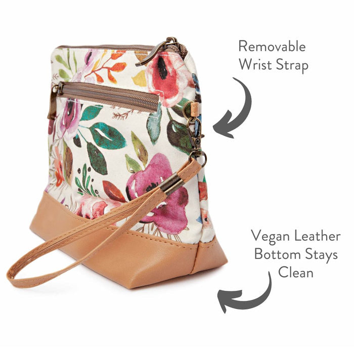 Spring Floral Mini Trini Bag side view showing the removable wrist strap, zippered exterior back pocket, and vegan leather bottom with annotated feature text