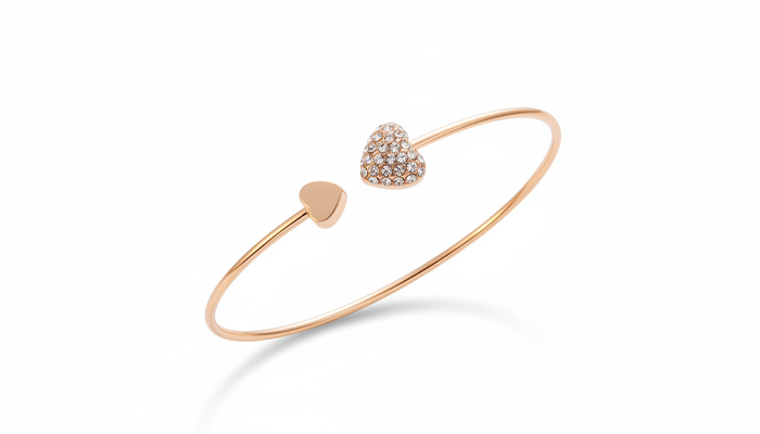 Open-ended rose gold heart bangle featuring one polished gold heart and one heart encrusted with shimmering pave crystals.