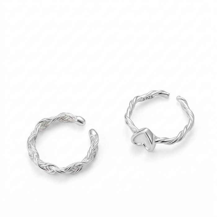 Two sterling silver adjustable rings, one braided-style band and one heart-motif twisted-band, on a pure white background.