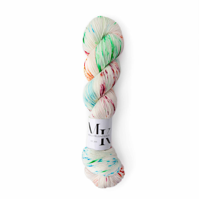 Skein of Molly Klein Dino Walk fingering weight yarn in white with rainbow speckled dye spots
