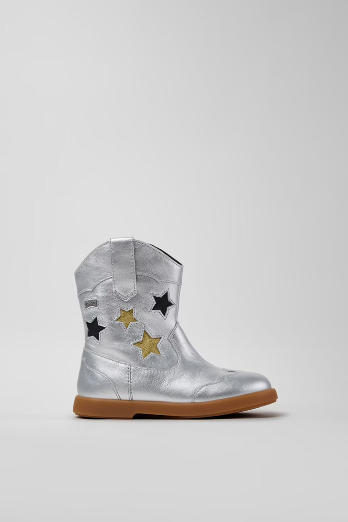 silver cowboy boot with gold and black stars on grey background.