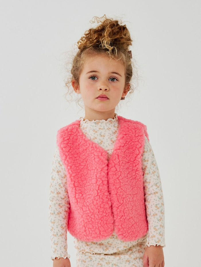 Young girl wearing a pink vest against a white background