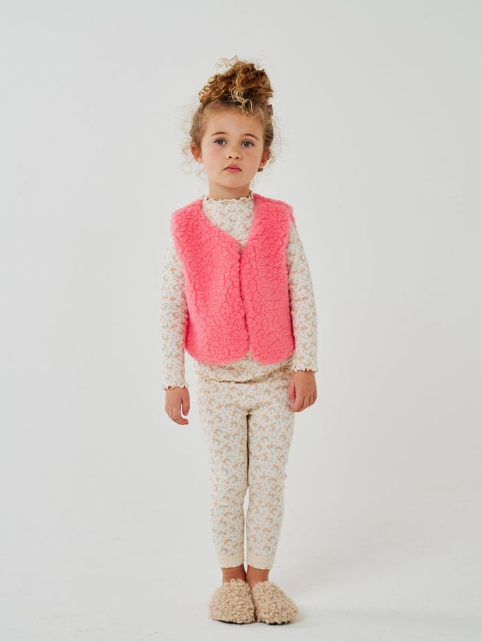 Young girl wearing a pink vest against a white background