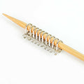Row of silver cast melody clip stitch markers lined up on bamboo knitting needle